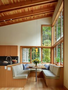 a living room filled with lots of furniture next to large windows on top of a wooden floor