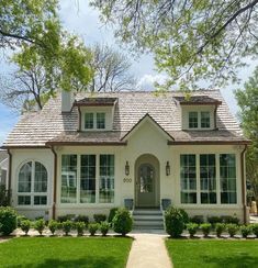 a white house with lots of windows on the front and side of it's roof