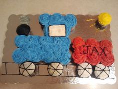 a cake shaped like a train with blue icing and red roses on the side