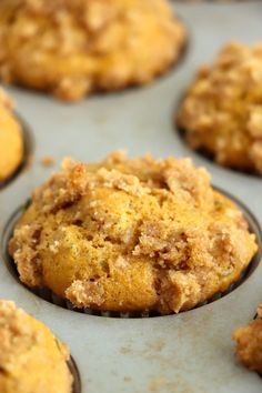 muffins with crumbs sitting on top of a baking pan filled with muffins