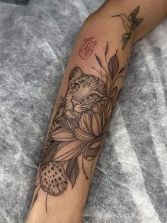 a woman's arm with a tattoo on it that has a cat and flowers