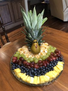 a pineapple sitting on top of a plate filled with grapes, bananas and other fruit