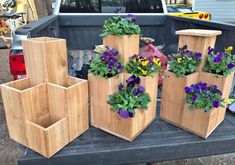 several wooden planters sitting on the back of a pickup truck with flowers in them