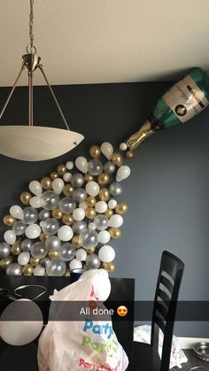 balloons are falling from the ceiling in front of a chandelier and table with black chairs