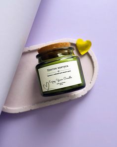 a jar of green candle sitting on top of a white tray next to a yellow heart