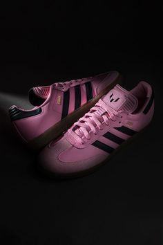 a pair of pink adidas sneakers on a black background