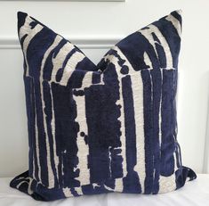 a blue and white pillow sitting on top of a bed next to a framed painting