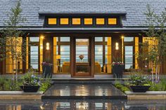 the front entrance of a house with potted plants and lights on it's windows