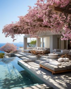 an outdoor lounge area with pink flowers on the trees