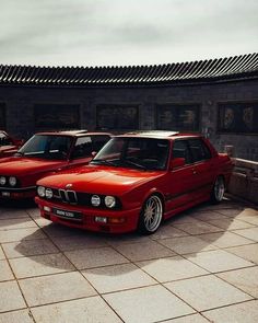 two red cars parked next to each other in front of a building