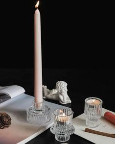 a lit candle sitting on top of a table next to some candles and other items