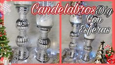 two silver candles sitting next to each other near a christmas tree and snowflakes