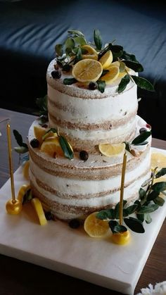 a three tiered cake with lemons and leaves on it sitting on a table