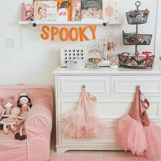 a baby's room decorated in pink and white with an orange spooky sign on the wall