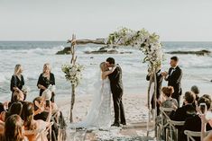 a bride and groom standing at the end of their wedding ceremony on the beach in front of the ocean