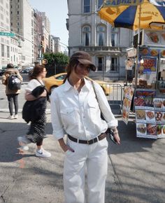 a woman standing on the sidewalk in front of a food stand