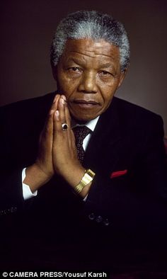 an older man wearing a suit and tie with his hands folded in front of him