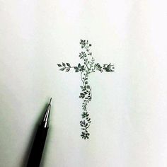 a drawing of a cross with flowers on it and a pen in the foreground