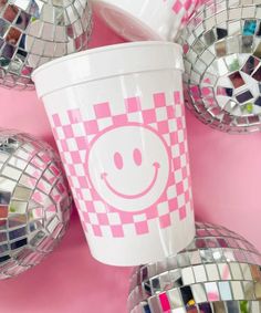 a cup with a smiley face on it surrounded by disco - ball balls and mirrors