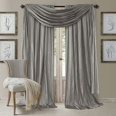 a chair sitting in front of a window covered in gray drapes and draperies