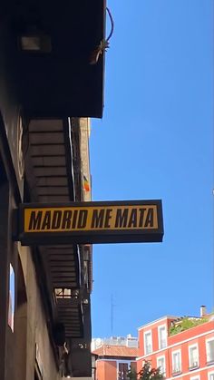 a yellow and black street sign hanging from the side of a building