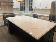 a kitchen with white marble counter tops and stainless steel appliances in the middle of it