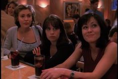 three women sitting at a table with drinks