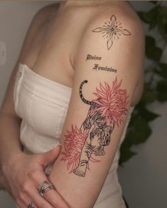 a woman with a tiger and flower tattoo on her arm, holding onto the arm