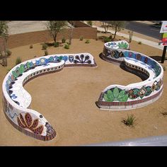 an artisticly designed bench sits in the middle of a park with cactus and flowers painted on it