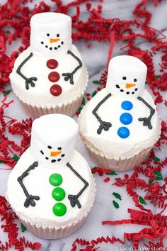 cupcakes decorated like snowmen on a red and white tablecloth