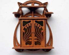 a wooden clock with an intricate design on it's face is shown against a white wall