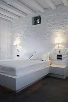 a white bed sitting in a bedroom next to two lamps on either side of it