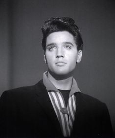 a black and white photo of a man in a suit looking up at the camera