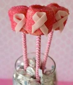 two candy lollipops in a glass with pink and white bows on them