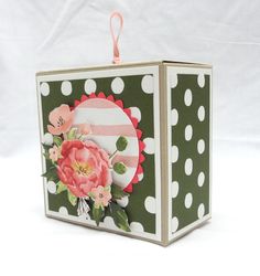 a small box with flowers and polka dots on the inside, hanging from a pink ribbon