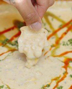 a person dipping something into a bowl with sauce