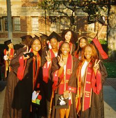 a group of women in graduation gowns posing for the camera with their hands up