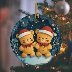 two teddy bears are hanging from a christmas ornament on a tree with lights