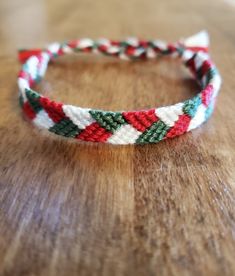 a red, white and green braided headband sitting on top of a wooden table