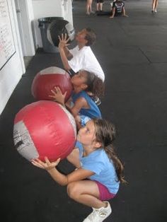 several children are playing with large balls on the sidewalk