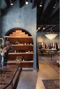 the inside of a clothing store with shelves filled with shoes and vases full of flowers