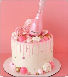 a cake decorated with pink icing, roses and a bottle of champagne on top