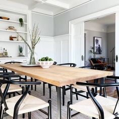 a dining room table with chairs and a bowl of fruit on top of the table