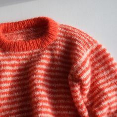 an orange and white striped sweater hanging on a wall