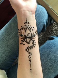 a woman's arm with a henna tattoo design on the left side of her wrist