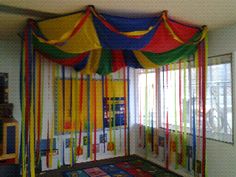 an indoor play area with multicolored drapes and rugs on the floor