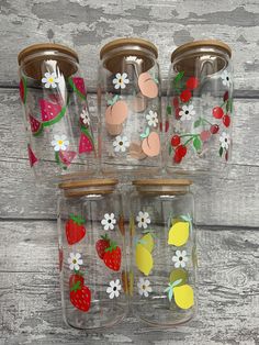 four glass jars with strawberries, lemons, and strawberrys painted on them