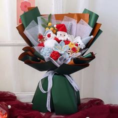 a bouquet of flowers is wrapped in green paper and sitting on a red table cloth