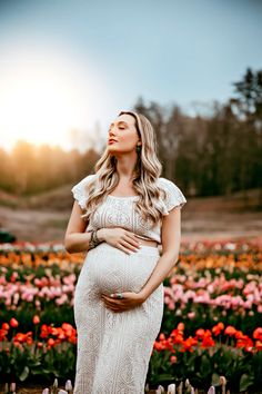 a pregnant woman standing in a field of tulips with her hands on her stomach