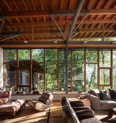 a living room filled with lots of furniture next to large glass windows on top of a wooden floor